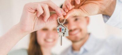 a happy couple holding their house key after buying and moving into a home